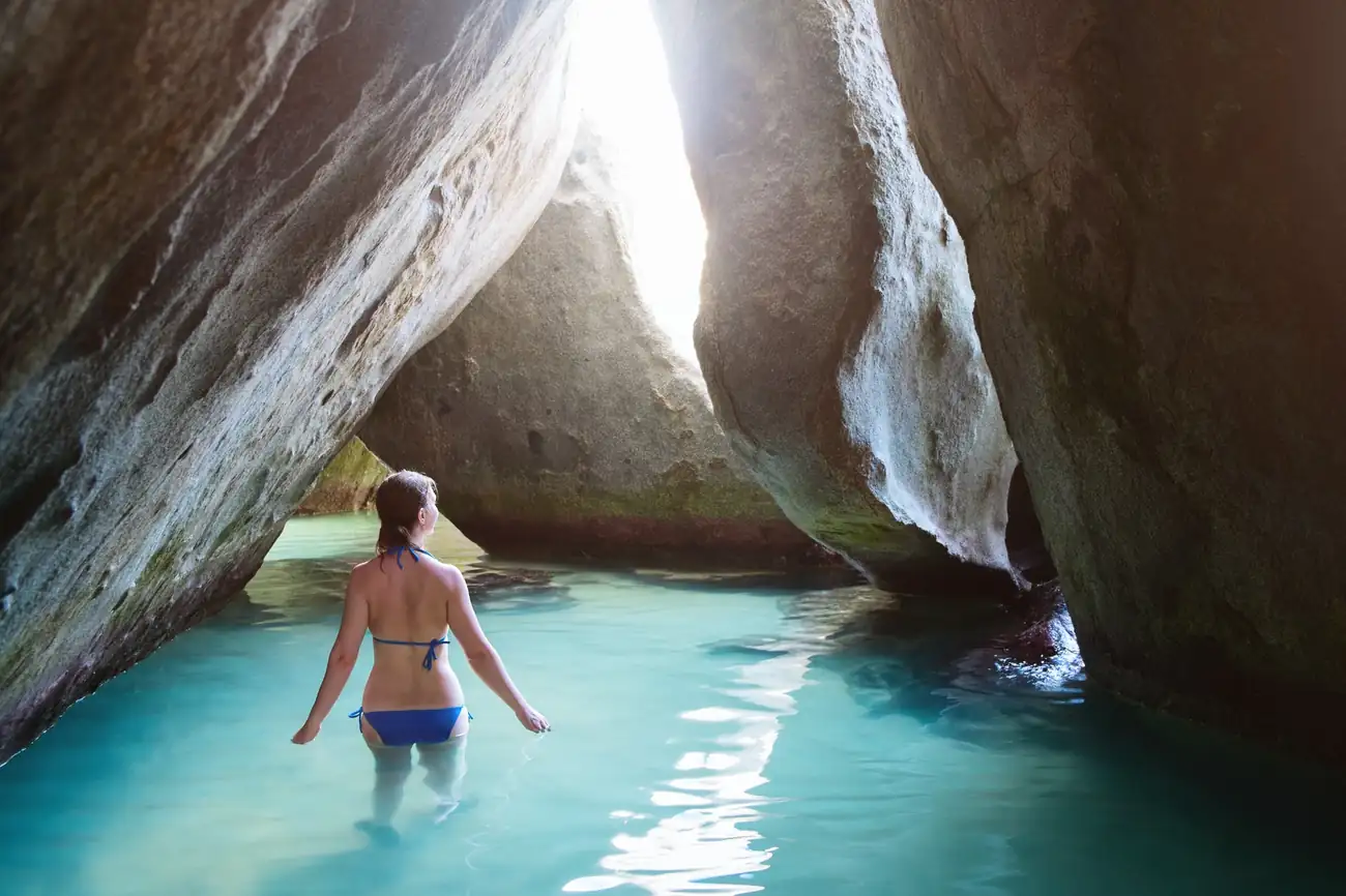 Woman exploring the granite boulders and shallow turquoise waters at The Baths on Virgin Gorda in the British Virgin Islands.