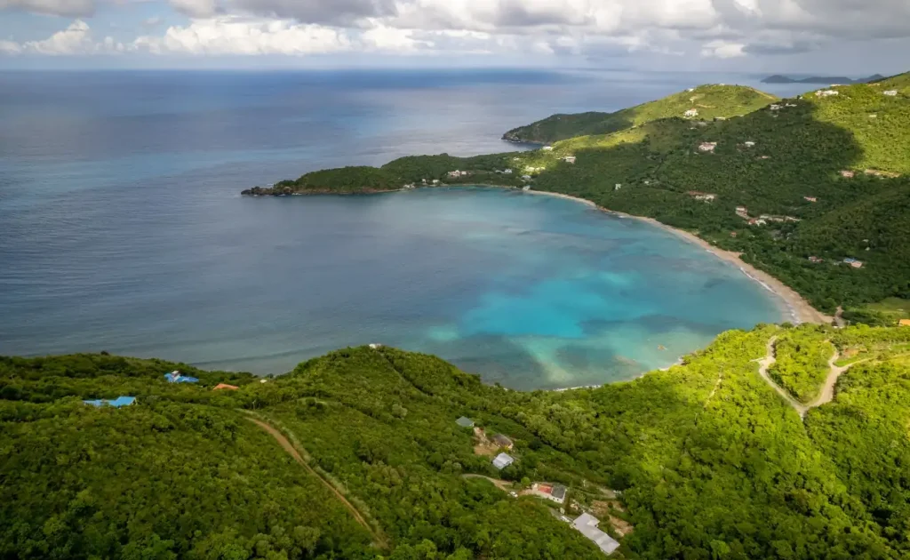 Aerial view of Brewer’s Bay with a wide crescent beach and turquoise waters on Tortola in the British Virgin Islands.